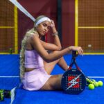 Young woman in pink on a padel court with racket and balls.