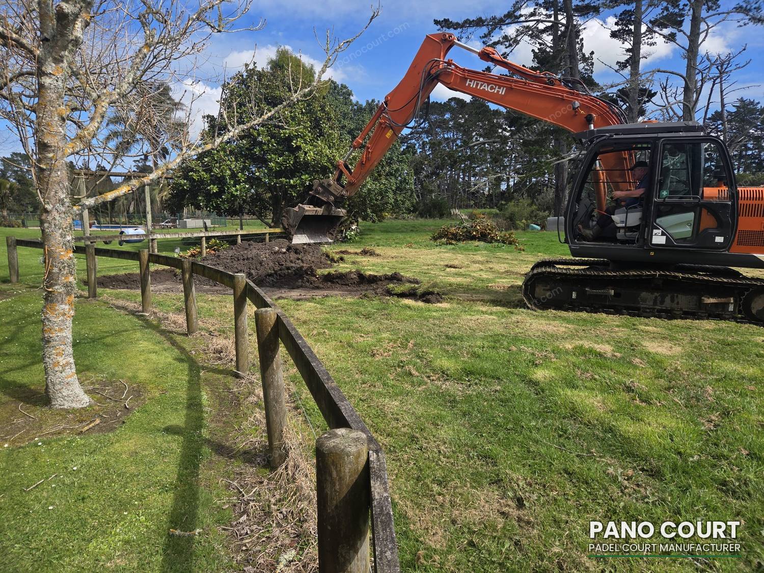 Excavator stripping topsoil to meet padel court foundation requirements before the slab is poured